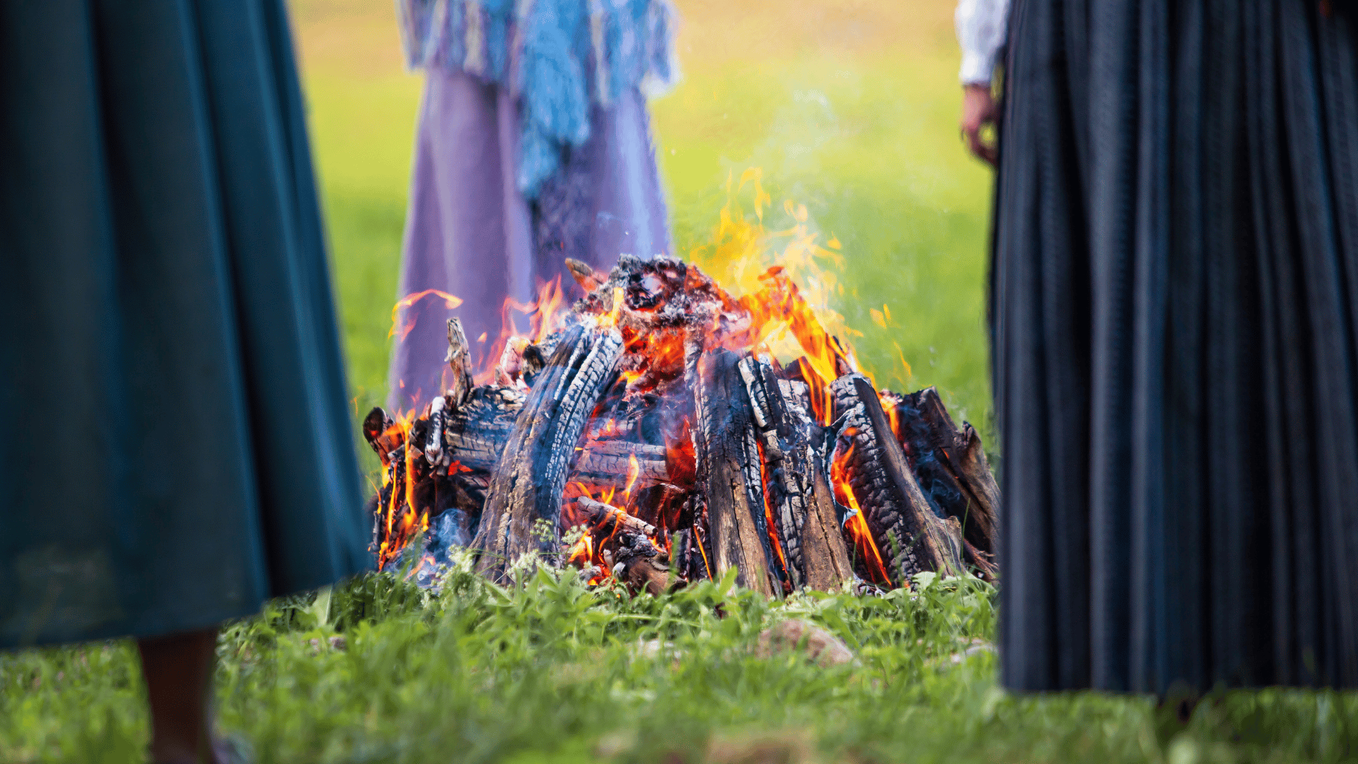 Three people around a bonfire.