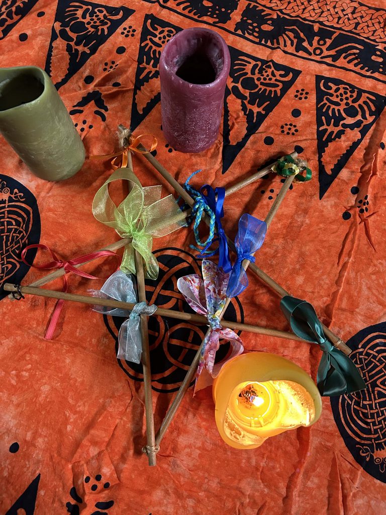 A craft star tied with ribbons next to a candle.