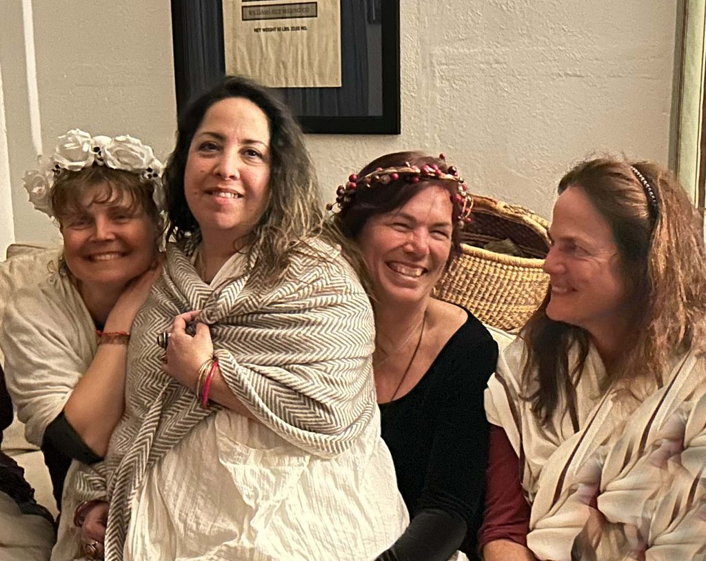 Four Priestesses sitting together smiling and laughing.